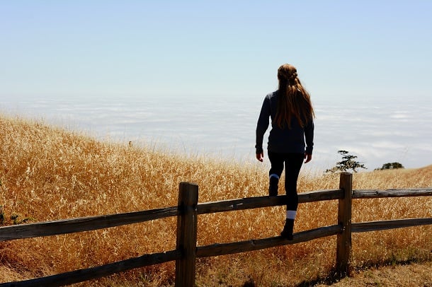 A woman stepping over a fence.