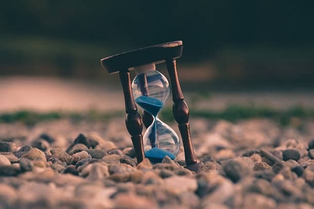 An hourglass standing on pebbles.