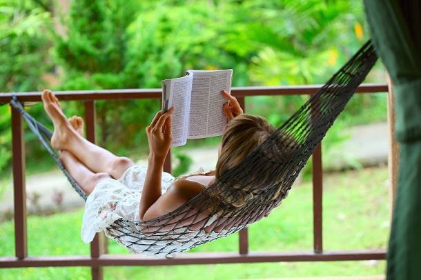 Woman reading a book while relaxing in a hammock.