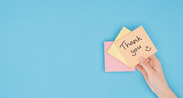 A hand holding a post-it note saying: Thank You!