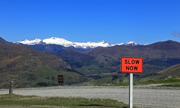 A road sign saying "Slow Now".