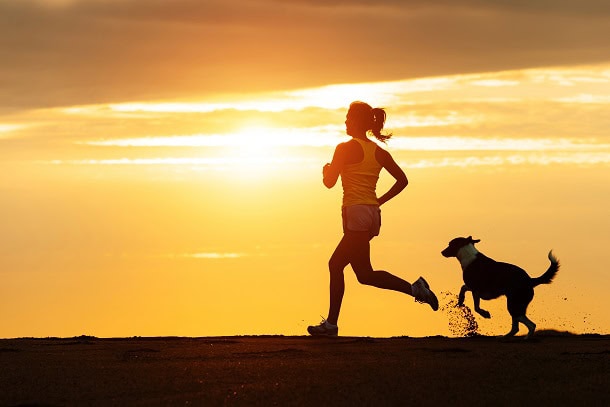 Woman on run in the sun with her dog.