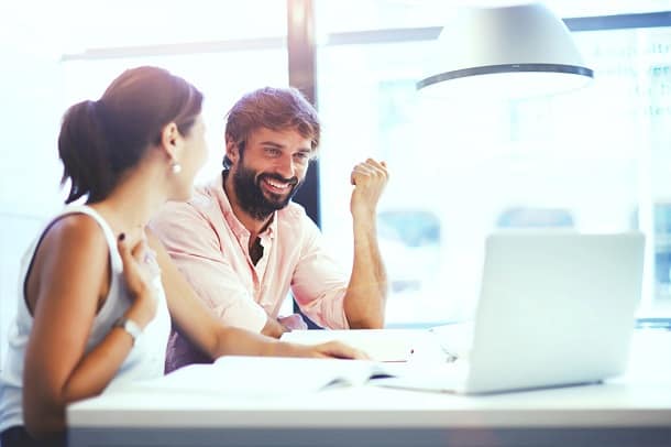 Two people working on a laptop and laughing about something.