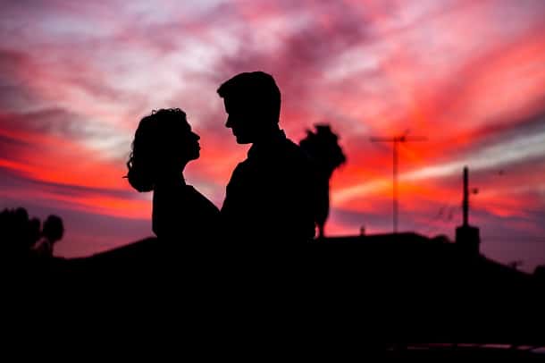 The silhouettes of a man and woman looking at each other during a sunset.