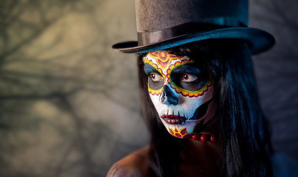 A young woman with a high hat and a her face painted for Halloween.