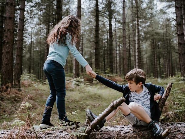 An image of a girl helping a boy up after he has fallen.