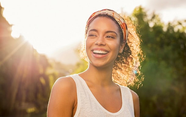 A smiling woman outside in the sunshine.