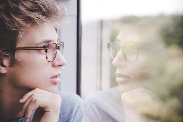 A man staring at himself reflected in the train window.