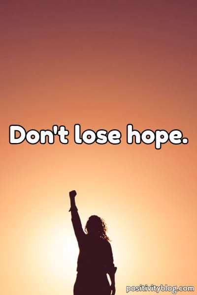 A woman with her fist raised and not losing hope.